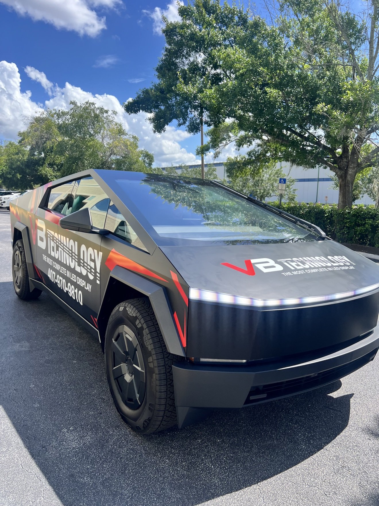 Tesla Cybertruck with a full commercial wrap for VB Technology, front three-quarter view