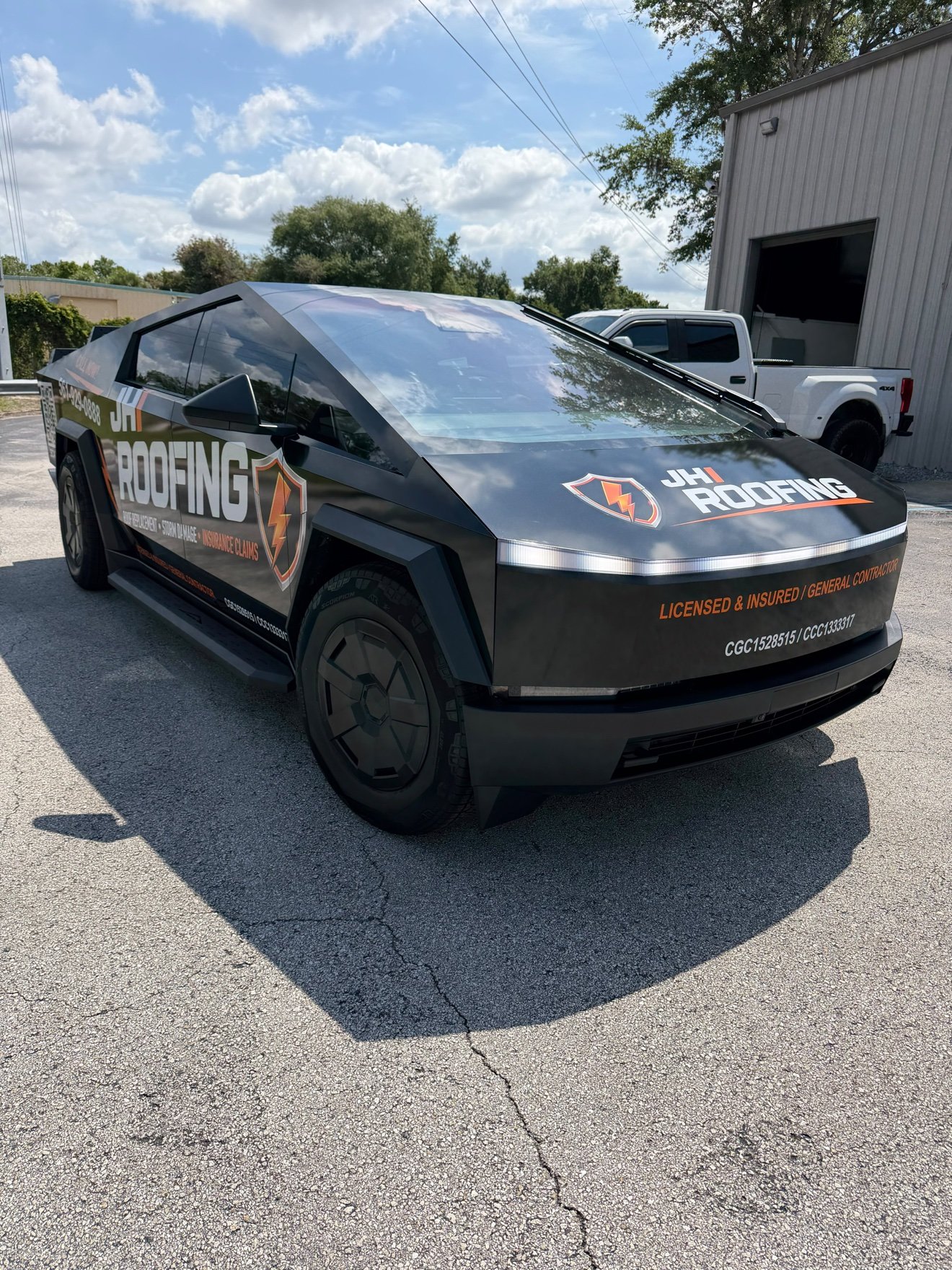 Tesla Cybertruck wrapped in black and orange for JH Roofing, front three-quarter view