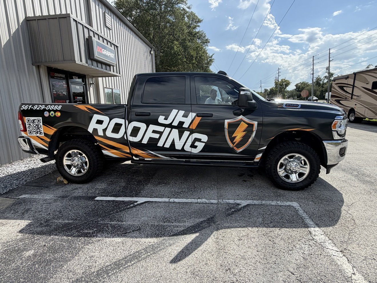 Ram 2500 pickup with a black and orange full wrap for JH Roofing