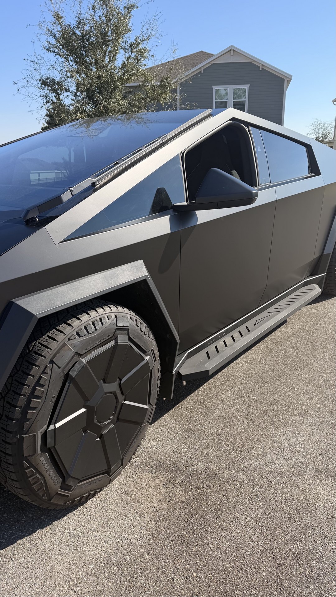 Tesla Cybertruck wrapped in matte black, side detail showing the front wheel and running board