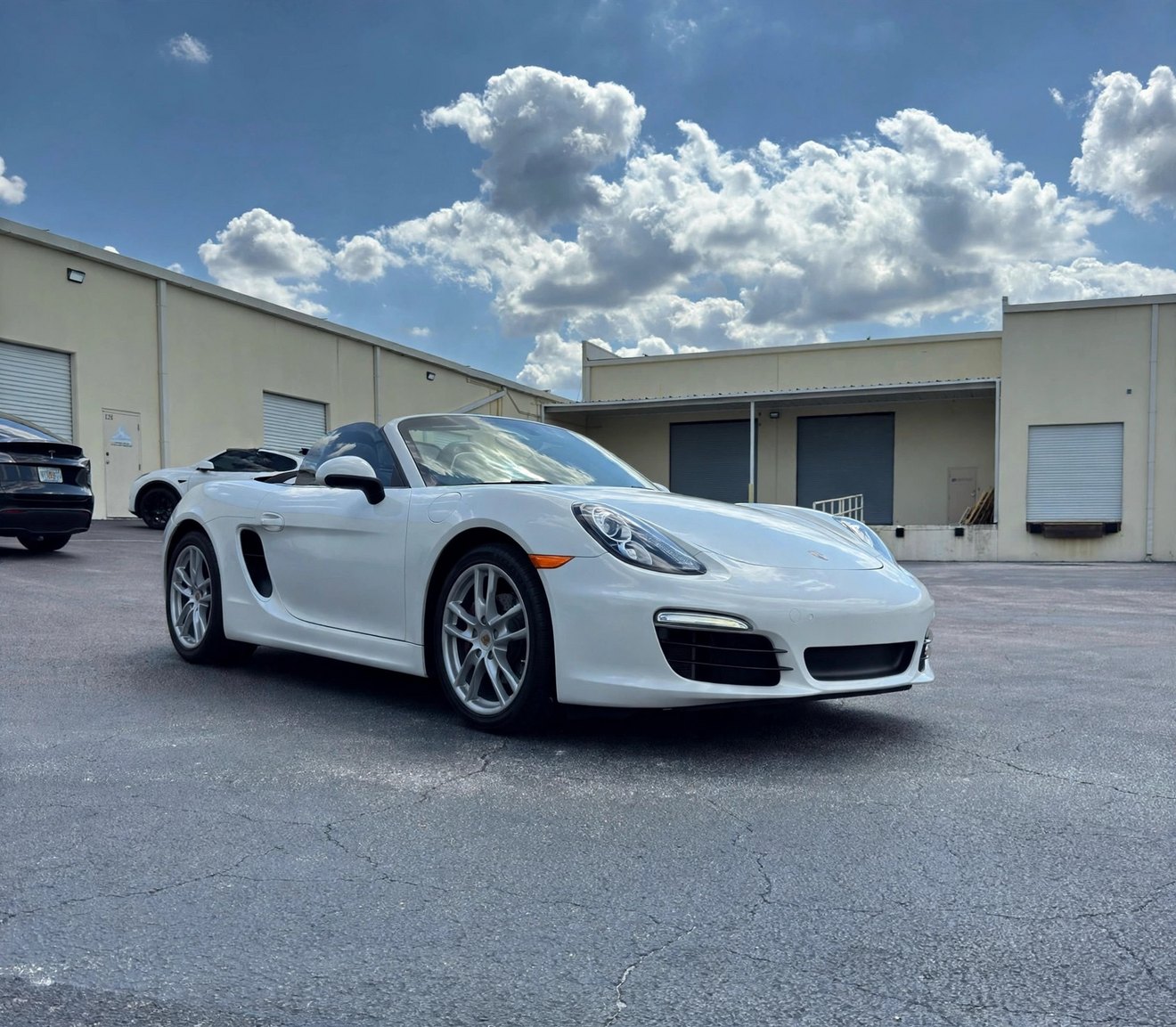 Porsche Boxster before the wrap, in its original glossy white factory paint with silver wheels, front three-quarter view