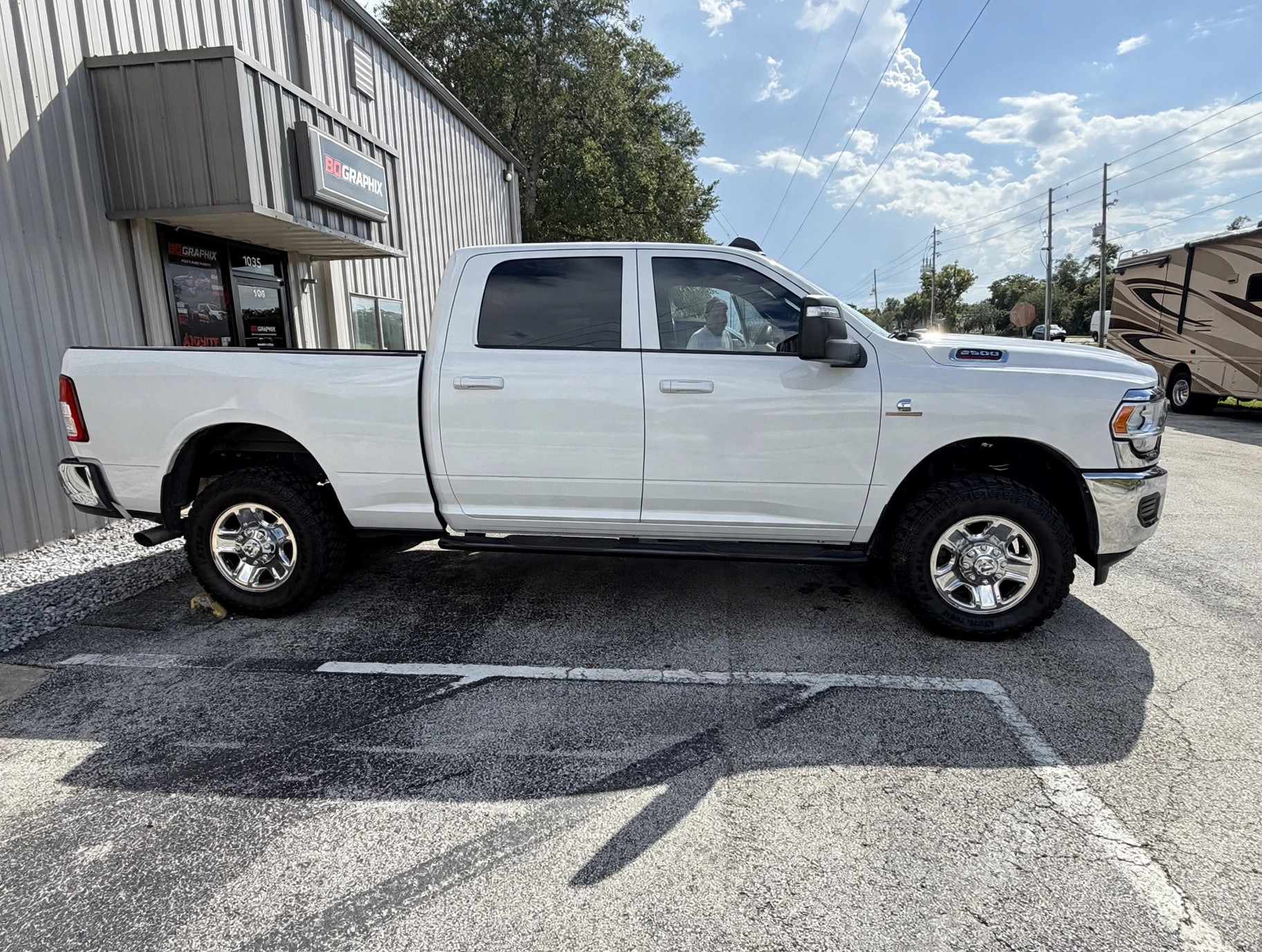Ram 2500 pickup before the wrap, in its original plain glossy white factory paint with no graphics, side view at the BQ Graphix shop