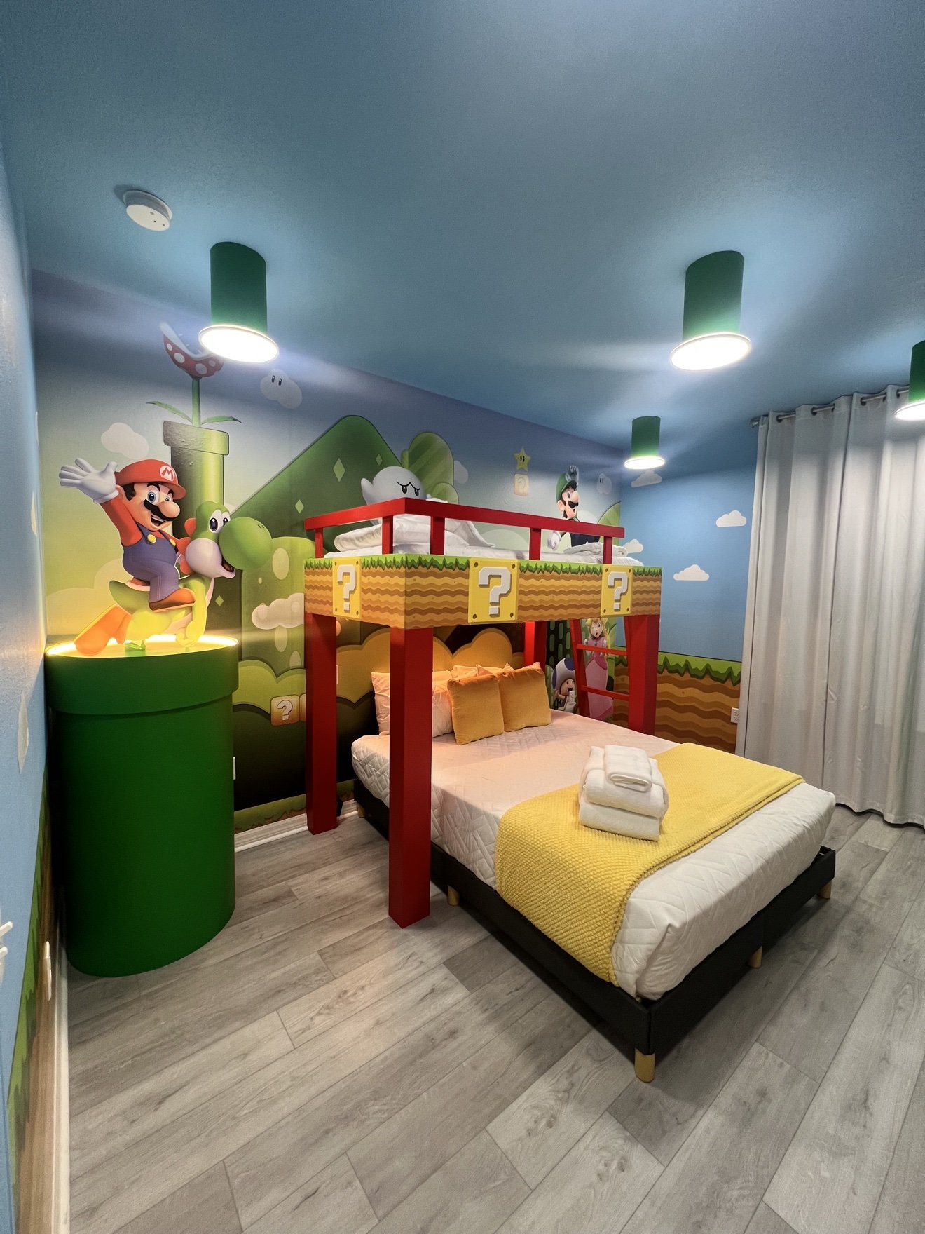 Super Mario themed bedroom with a question-block bunk bed, a green warp pipe and Mario riding Yoshi on the wall