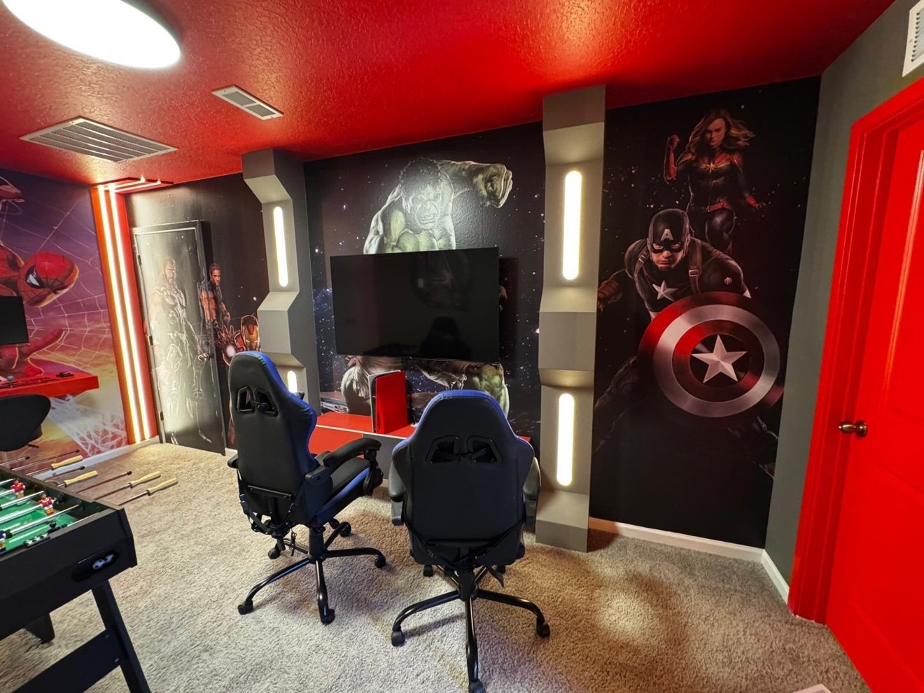 Avengers game room with gaming chairs in front of comic-style superhero wall art