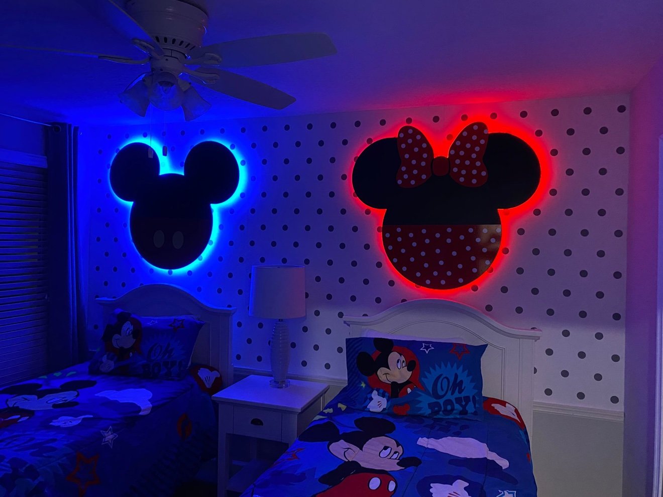 Mickey head cutout with blue LED backlight and Minnie head cutout with red LED backlight mounted above twin beds