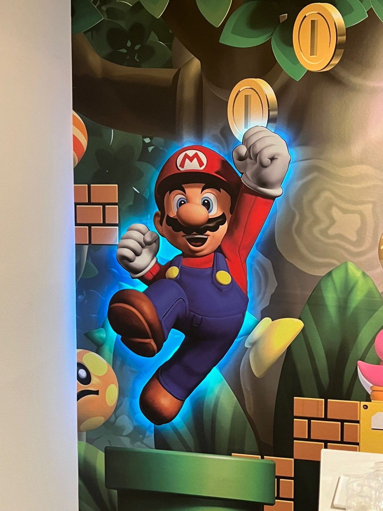 Mario jumping 3D cutout with a blue LED glow mounted over a mural wall