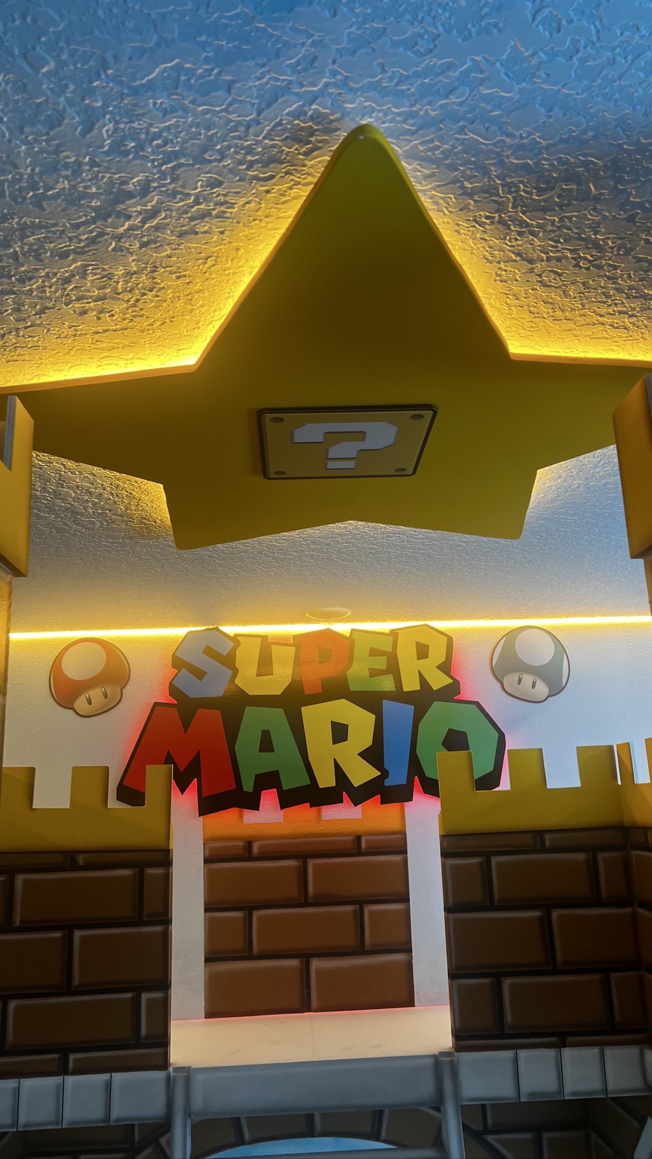 Super Mario logo sign with LED strip lighting under a star-shaped ceiling light